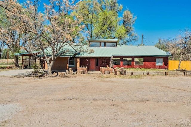 view of front of property featuring a porch, dirt driveway, and metal roof