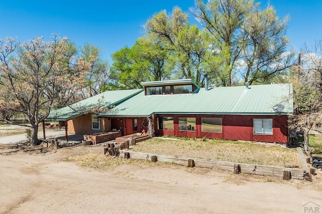 view of front of house with metal roof, driveway, and a carport