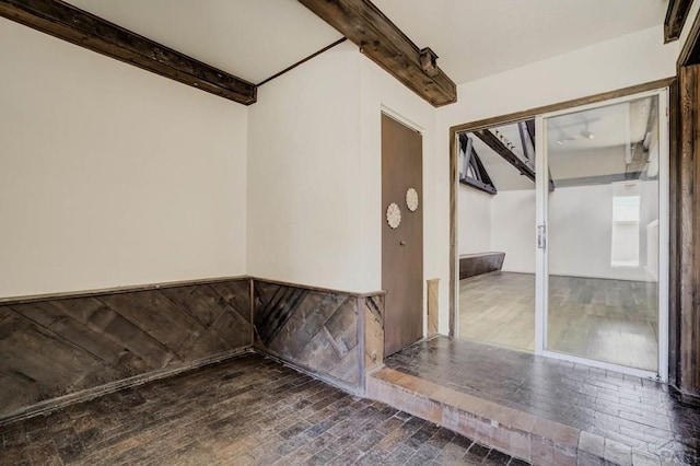 spare room featuring wood-type flooring and beam ceiling