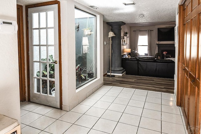 doorway featuring light tile patterned floors, a textured ceiling, and a fireplace