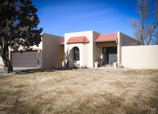 view of front of home with a tiled roof, an attached garage, fence, a front lawn, and stucco siding