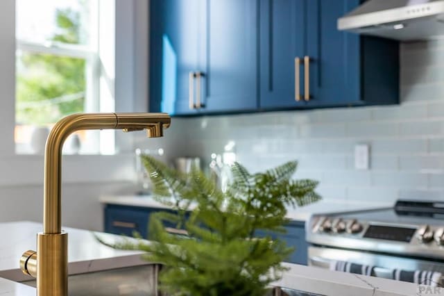 room details with tasteful backsplash, blue cabinets, stainless steel electric stove, extractor fan, and light countertops