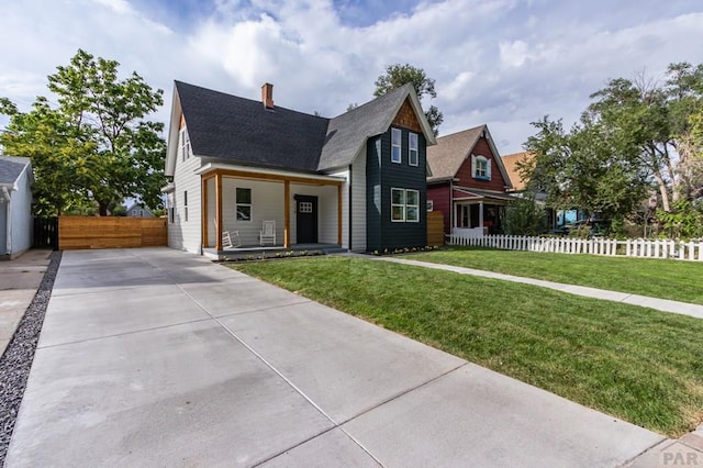 view of front facade featuring a shingled roof, a front yard, and fence