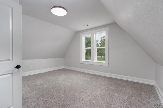 additional living space with lofted ceiling, carpet flooring, visible vents, and baseboards