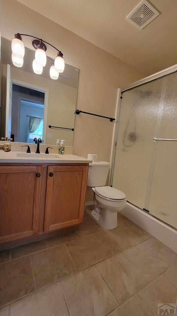 full bathroom with visible vents, toilet, tile patterned floors, vanity, and a shower stall