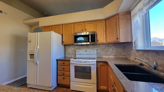 kitchen featuring white appliances, a sink, visible vents, light stone countertops, and tasteful backsplash