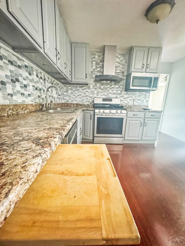 19 Cornell Cir, Pueblo, CO 81005 - kitchen with stainless steel appliances, wall chimney exhaust hood, backsplash, dark wood-type flooring, and gray cabinets