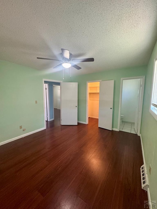 19 Cornell Cir, Pueblo, CO 81005 - unfurnished bedroom with wood finished floors, a spacious closet, a textured ceiling, a closet, and a ceiling fan