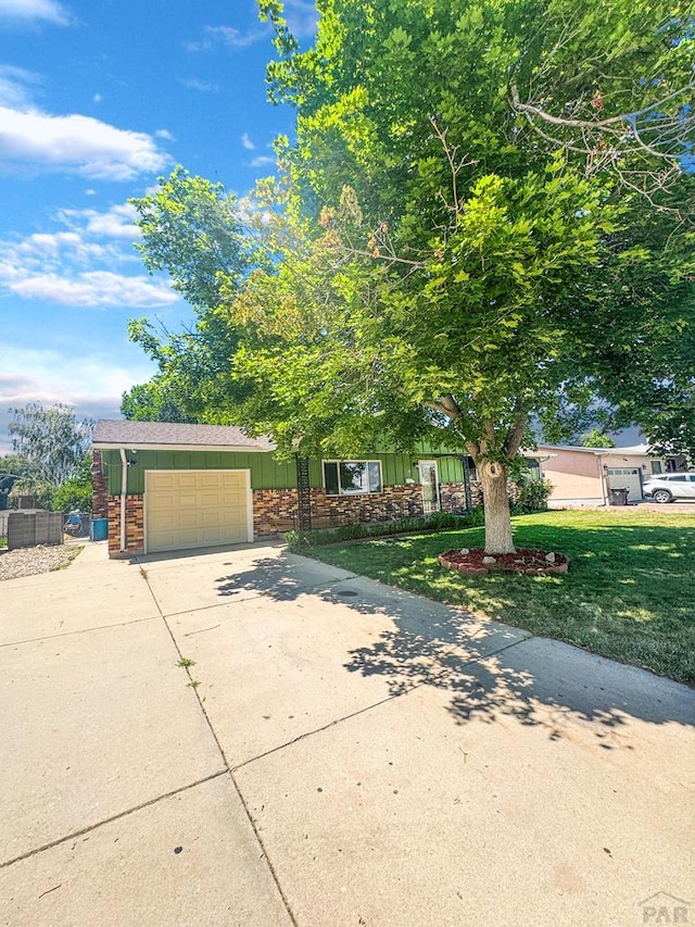 19 Cornell Cir, Pueblo, CO 81005 - view of front of property with concrete driveway, a garage, board and batten siding, and a front lawn