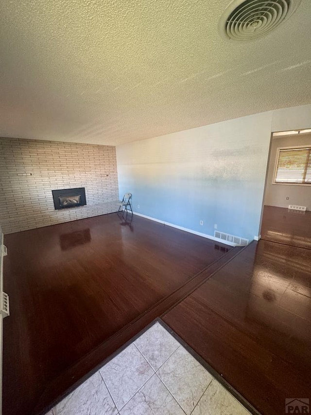 19 Cornell Cir, Pueblo, CO 81005 - unfurnished living room with a textured ceiling, a brick fireplace, and tile patterned flooring