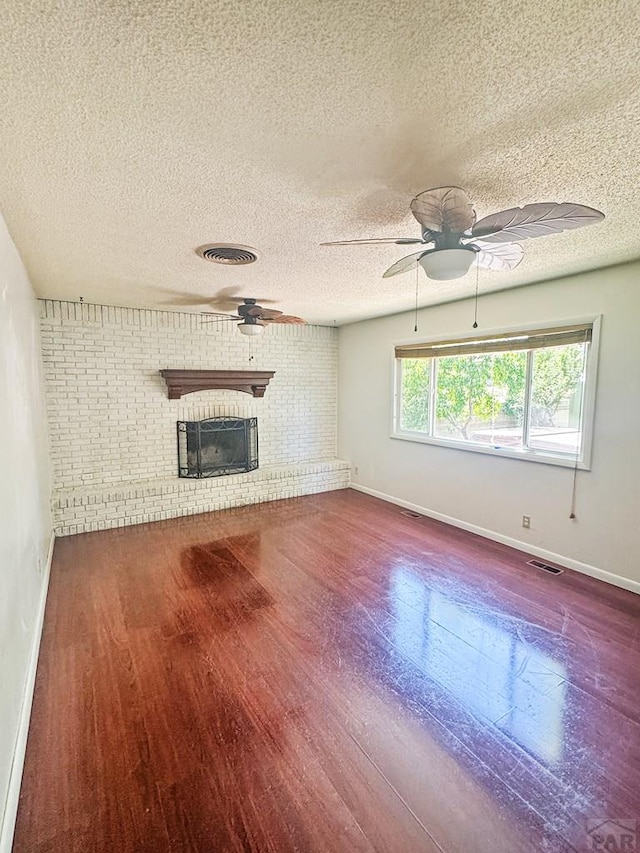 19 Cornell Cir, Pueblo, CO 81005 - unfurnished living room with wood finished floors, a fireplace, ceiling fan, a textured ceiling, and brick wall