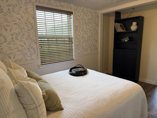 402 Alma Ave, Pueblo, CO 81004 - bedroom with wallpapered walls, wainscoting, and wood finished floors