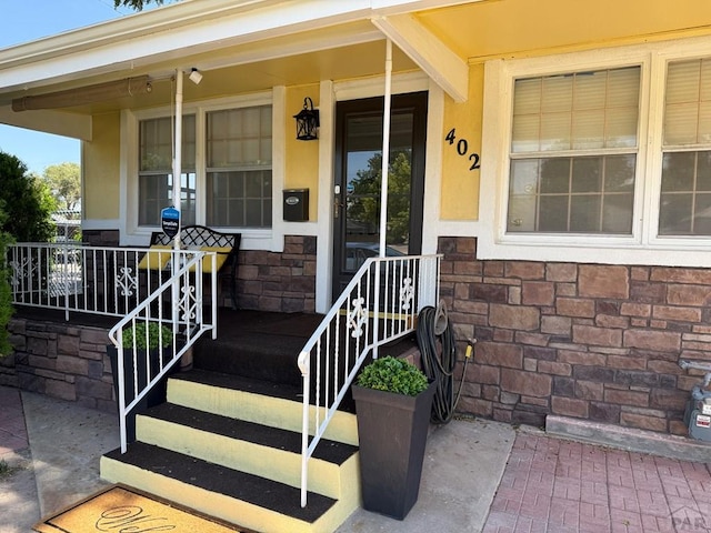 402 Alma Ave, Pueblo, CO 81004 - property entrance featuring a porch, stone siding, and stucco siding