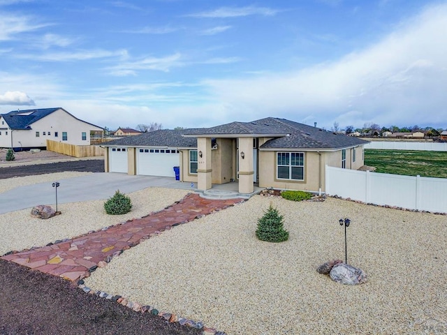 view of front facade with a garage, concrete driveway, stucco siding, and fence