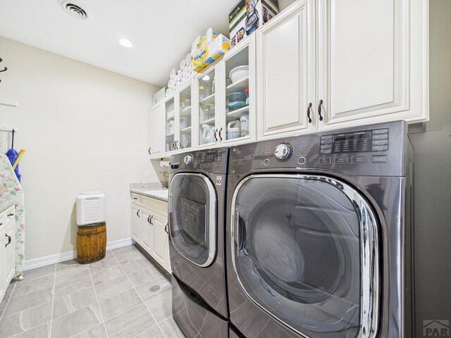 clothes washing area featuring baseboards, cabinet space, visible vents, and separate washer and dryer