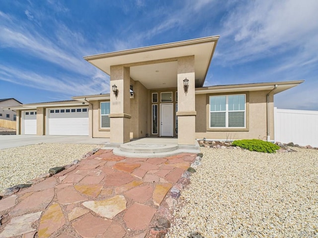 view of front facade with fence, driveway, stucco siding, and an attached garage