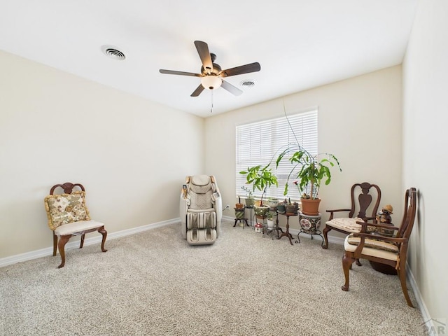 living area with carpet flooring, visible vents, baseboards, and ceiling fan