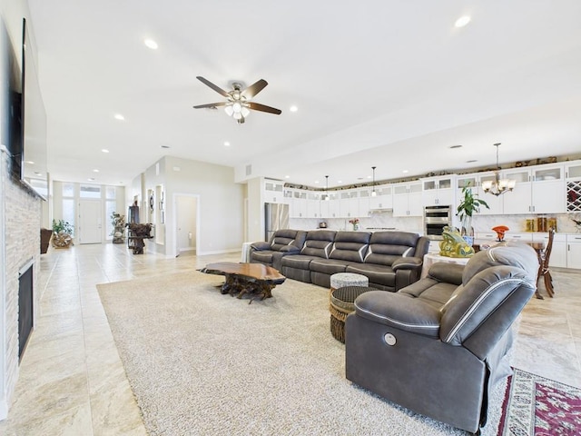 living room featuring a stone fireplace, ceiling fan with notable chandelier, and recessed lighting