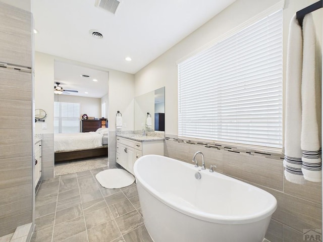 ensuite bathroom featuring ensuite bathroom, visible vents, tile walls, and vanity