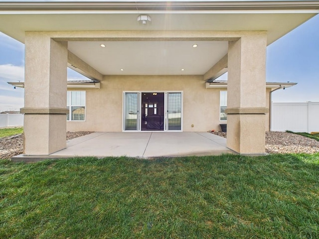 back of house featuring a patio, stucco siding, and a yard