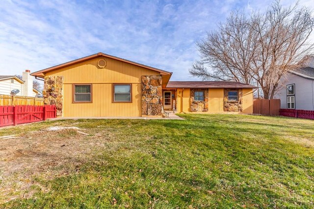 back of property featuring stone siding, a fenced backyard, and a yard