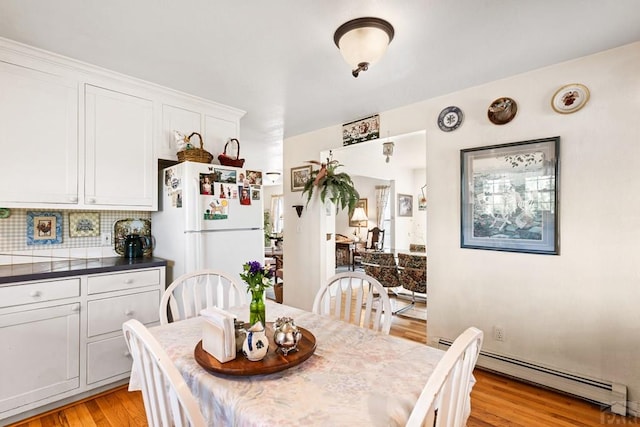 dining room with light wood finished floors and a baseboard radiator