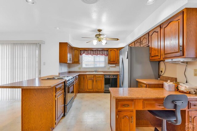 kitchen featuring a breakfast bar area, light countertops, appliances with stainless steel finishes, brown cabinetry, and a sink