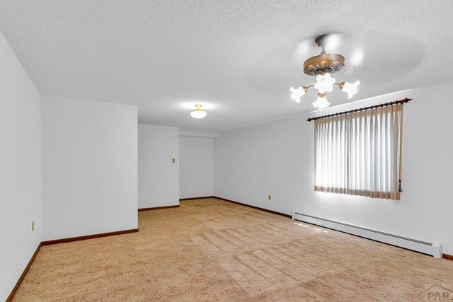 unfurnished room featuring a textured ceiling, light colored carpet, a baseboard heating unit, baseboards, and an inviting chandelier