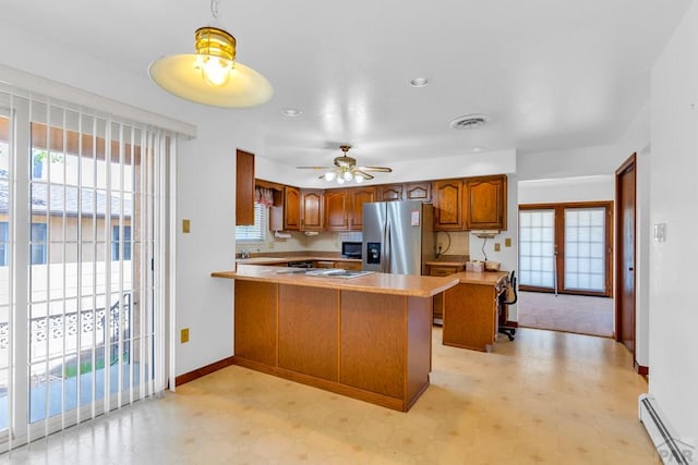 kitchen with stainless steel fridge, brown cabinetry, a peninsula, baseboard heating, and light countertops