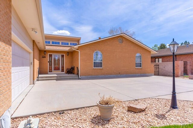 rear view of house featuring a garage, brick siding, and fence