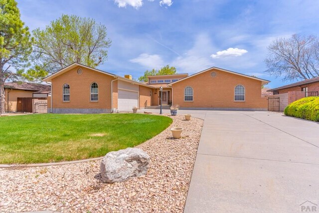 ranch-style house with an attached garage, concrete driveway, a front yard, and fence