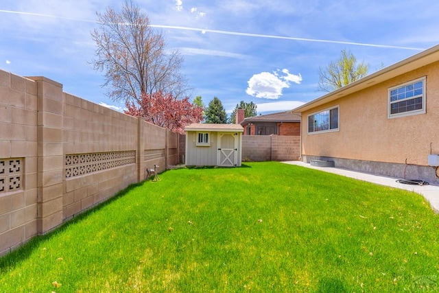 view of yard with a fenced backyard, a storage unit, and an outbuilding