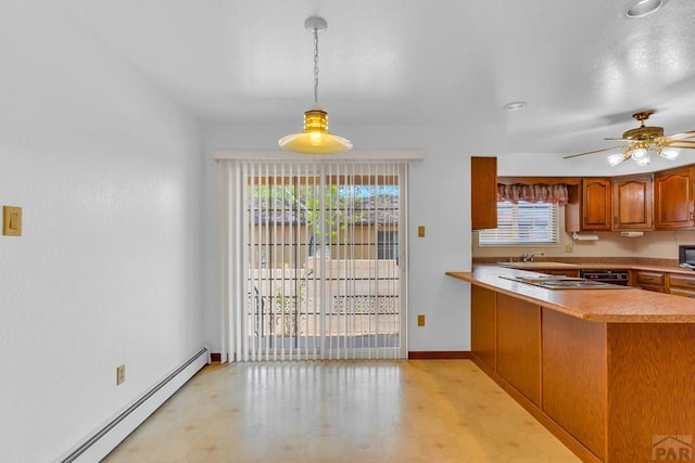 kitchen with brown cabinets, decorative light fixtures, light countertops, baseboard heating, and a peninsula