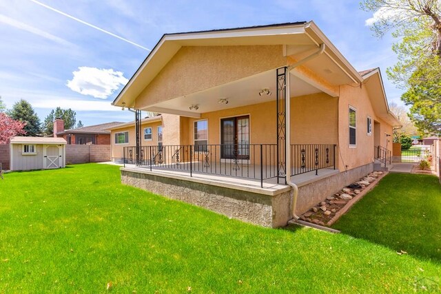 back of property featuring fence, a storage shed, and stucco siding