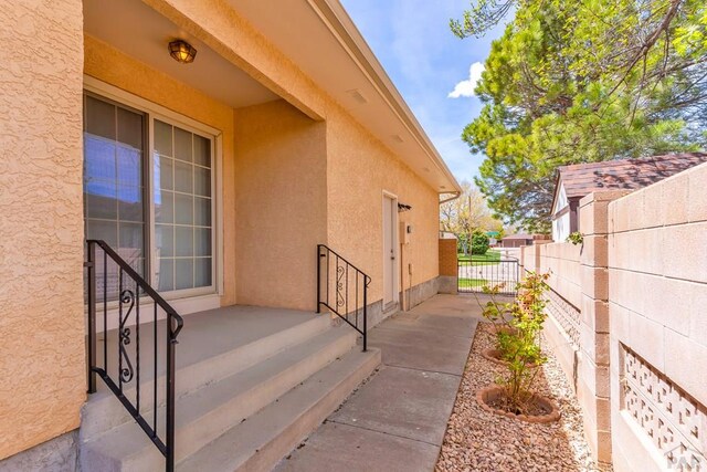 view of exterior entry featuring fence and stucco siding