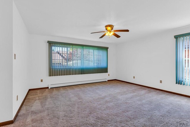 empty room with a baseboard radiator, light colored carpet, plenty of natural light, and baseboards