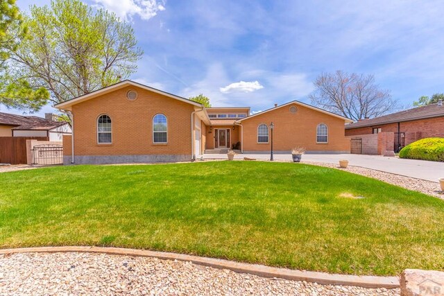 view of front of home featuring brick siding, fence, and a front lawn