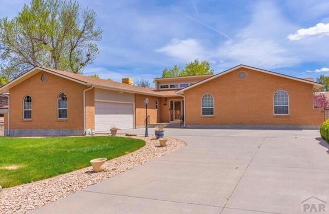 ranch-style home featuring a garage, concrete driveway, and a front yard