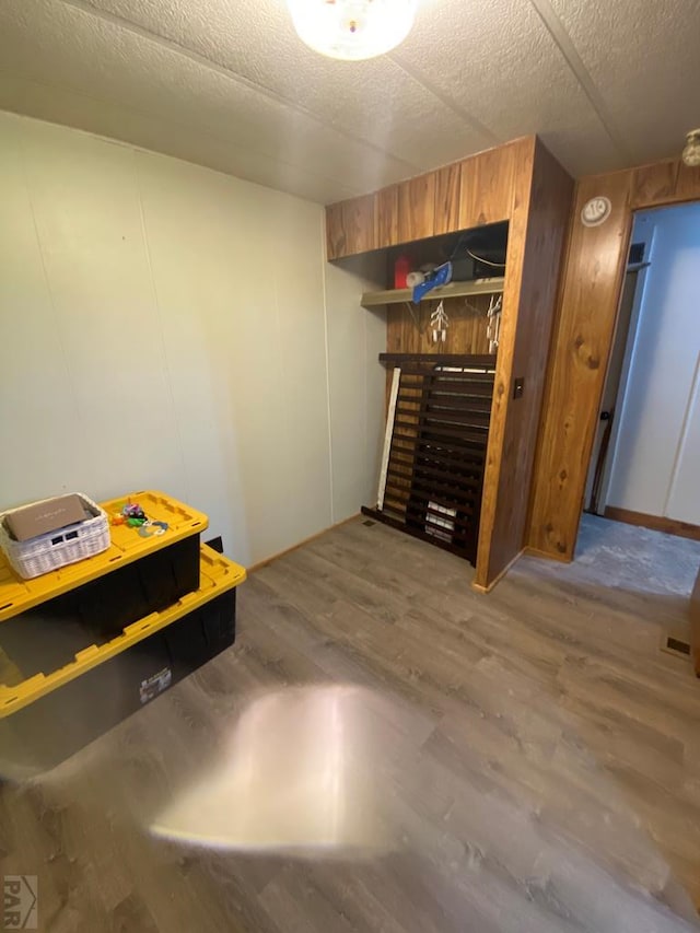 interior space with a textured ceiling, wood walls, and wood finished floors