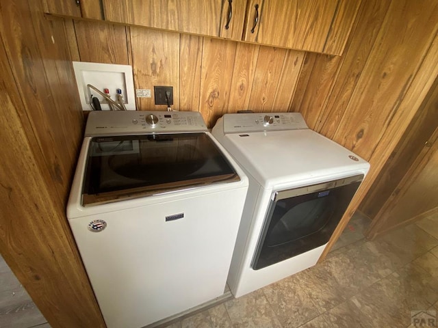 clothes washing area with laundry area, wooden walls, and independent washer and dryer