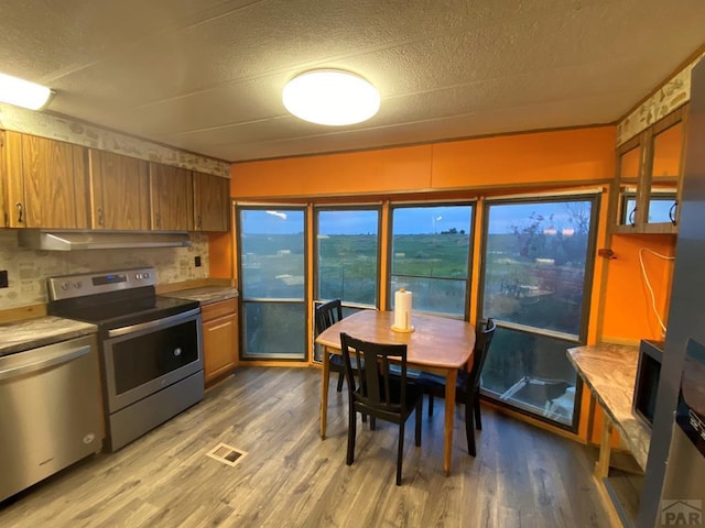 kitchen featuring appliances with stainless steel finishes, wood finished floors, visible vents, and brown cabinets