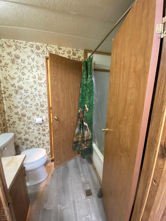 bathroom with shower / tub combo, wallpapered walls, wood finished floors, and vanity