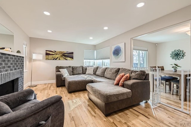 living area featuring baseboards, a fireplace, light wood-style flooring, and recessed lighting