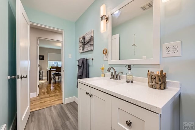 bathroom with baseboards, visible vents, wood finished floors, and vanity