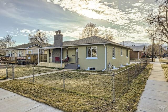 view of front of home with a fenced front yard, a residential view, a chimney, roof with shingles, and stucco siding