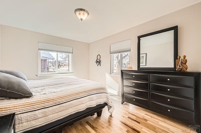 bedroom with multiple windows and light wood finished floors