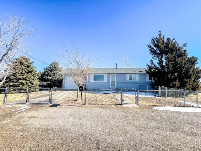 single story home with a fenced front yard, brick siding, a gate, a garage, and driveway