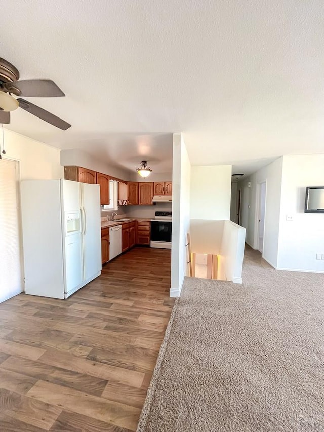 kitchen featuring white appliances, open floor plan, wood finished floors, light countertops, and a textured ceiling