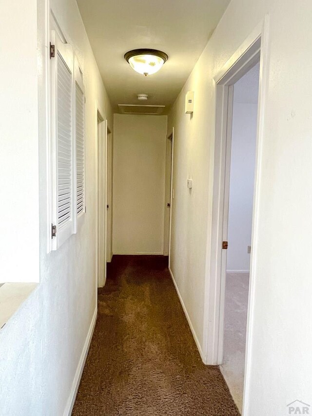 hall with dark carpet and baseboards