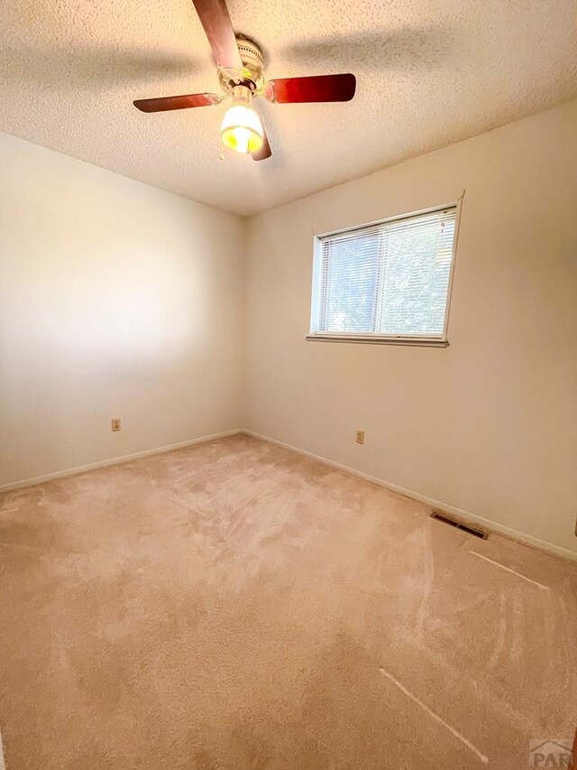 unfurnished room featuring visible vents, a textured ceiling, and carpet flooring